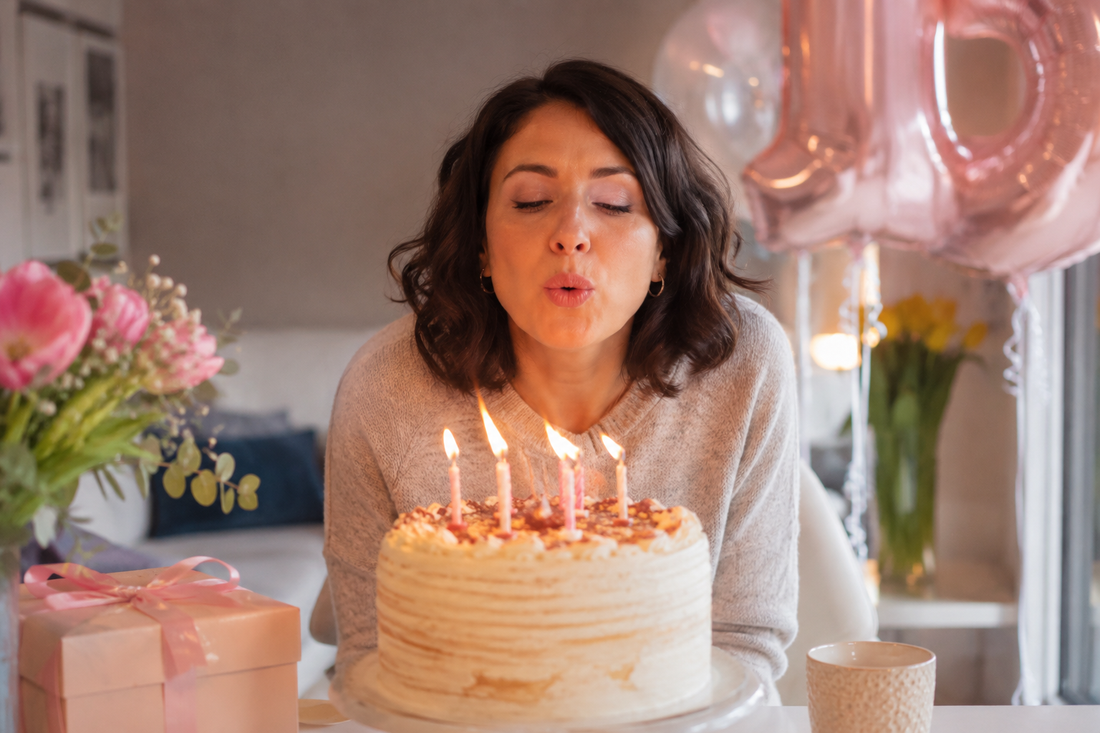Mamma che spegne le candeline sulla torta durante una festa di compleanno in casa.