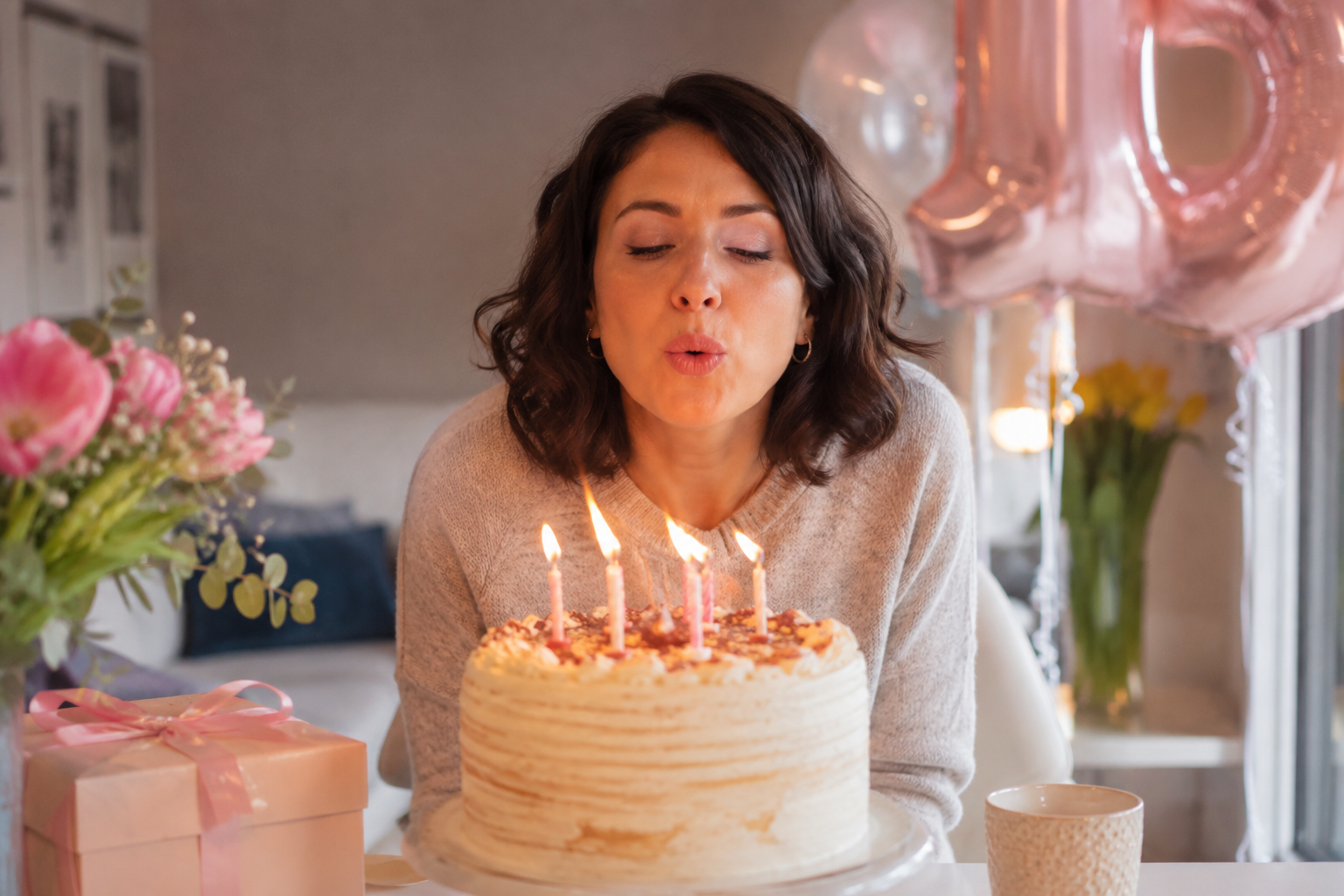 Mamma che spegne le candeline sulla torta durante una festa di compleanno in casa.